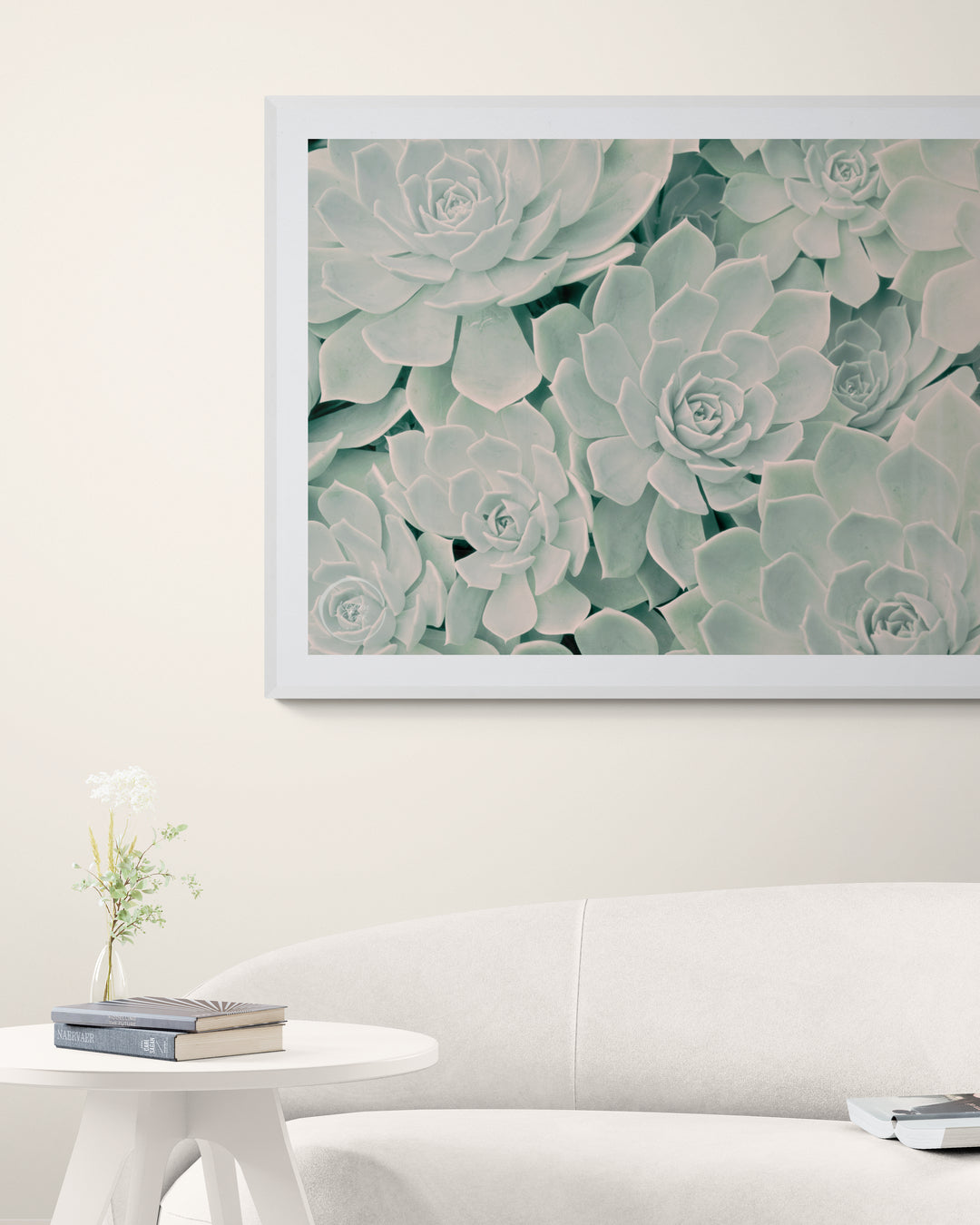 Succulent fine art print styled above a curved white sofa in a minimalist, neutral-toned living room.