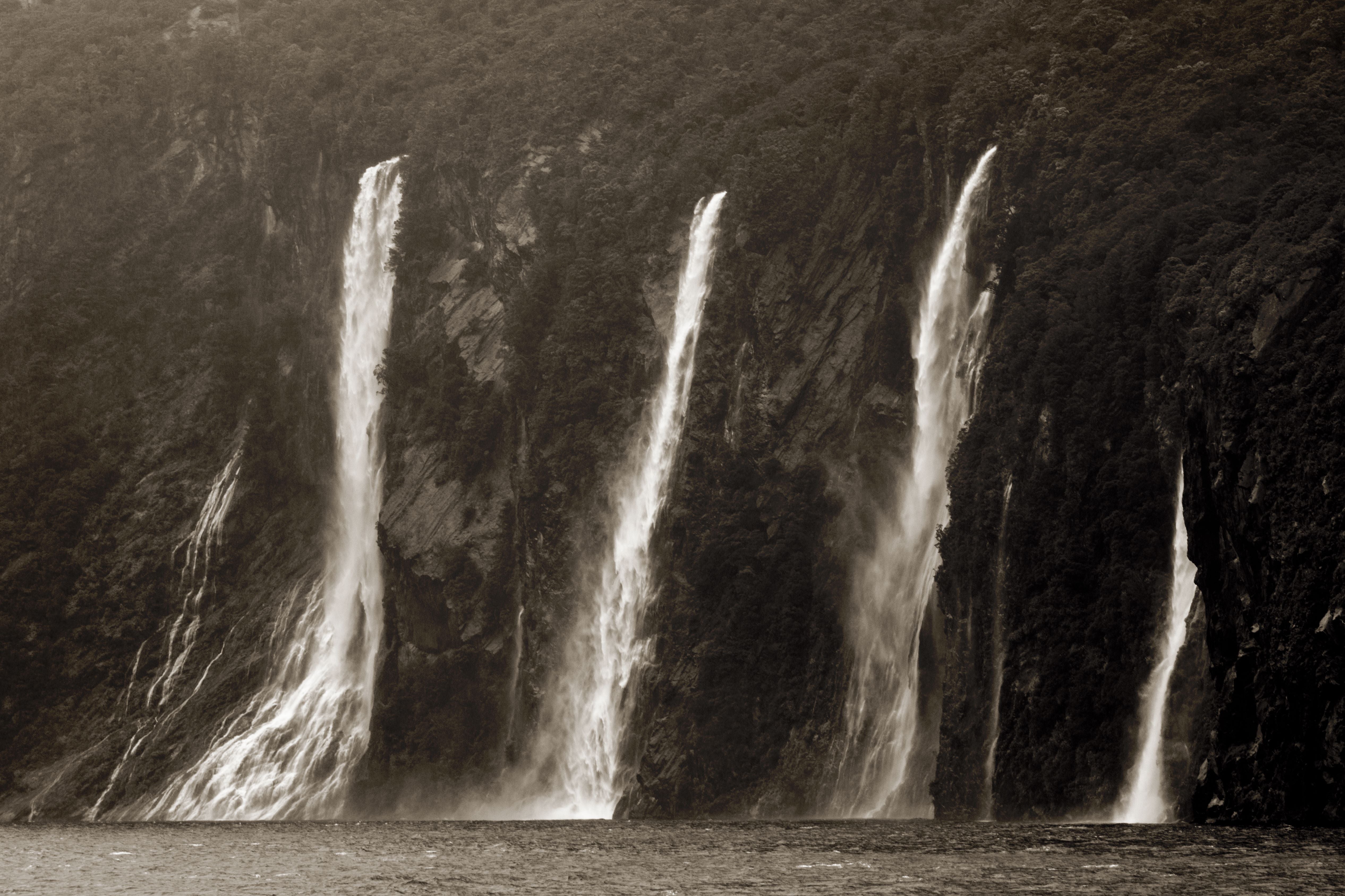 Black and white image of a waterfall with multiple streams cascading down a rocky cliff.